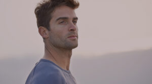 Confident young man looking into the distance at sunrise, representing focus and vitality — themes related to optimal testosterone levels and hormone health.